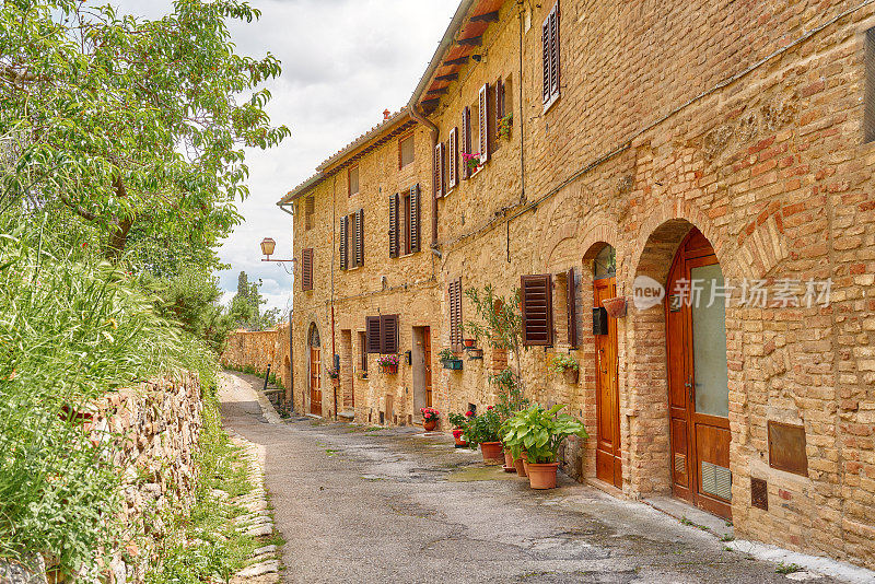 圣吉米尼亚诺(San Gimignano)的老路两旁是绿色的树篱和一座中世纪的石头房子